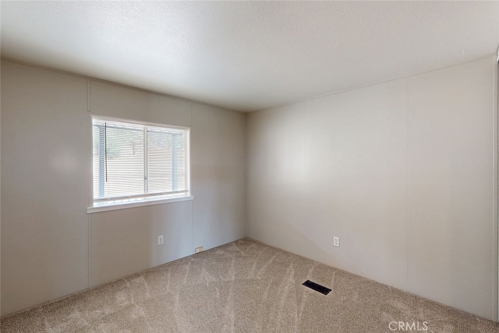 Empty carpeted room with a window and horizontal blinds.
