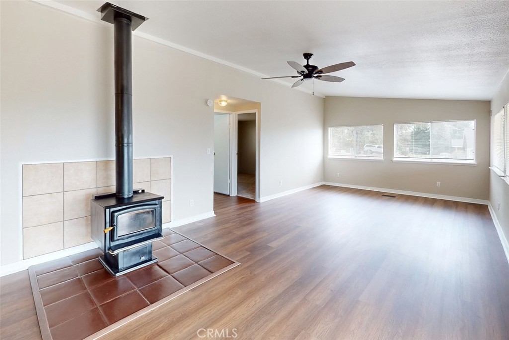 Empty living room with a freestanding wood stove on a large tiled hearth.