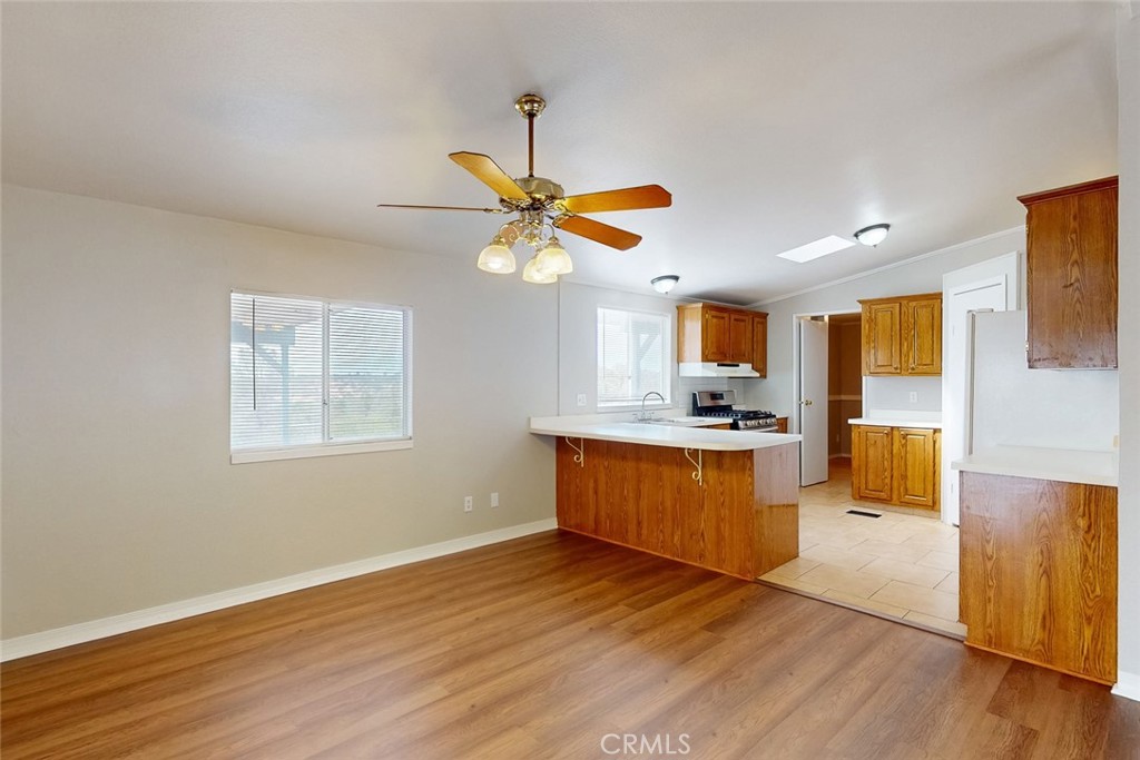 Vacant kitchen and dining area with honey-colored cabinets, a white peninsula, and wood-look flooring.