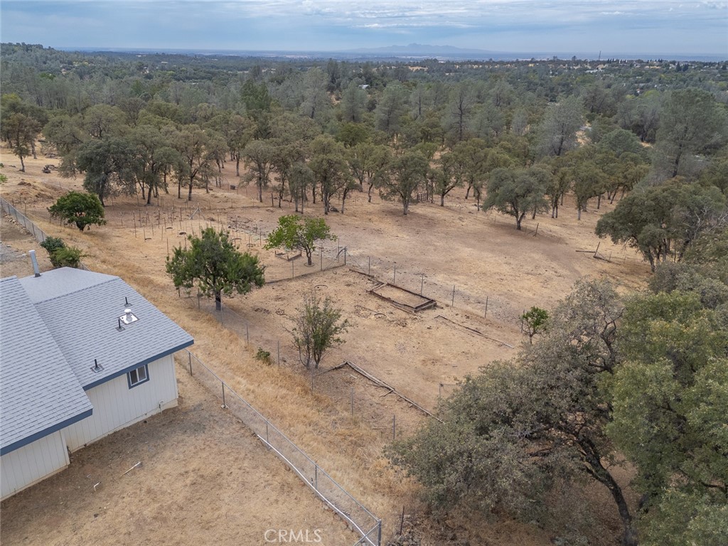 Aerial view of fenced acreage with scattered oak trees and a house at the edge.