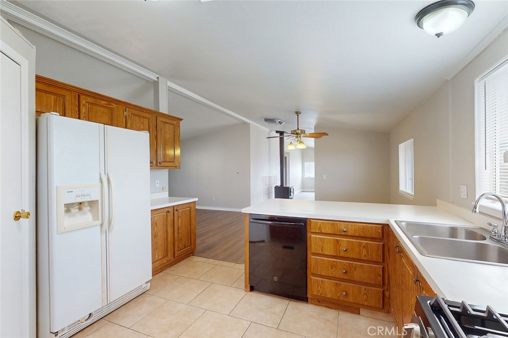 Kitchen with honey-toned cabinets, a central island, white refrigerator, and double-basin sink.