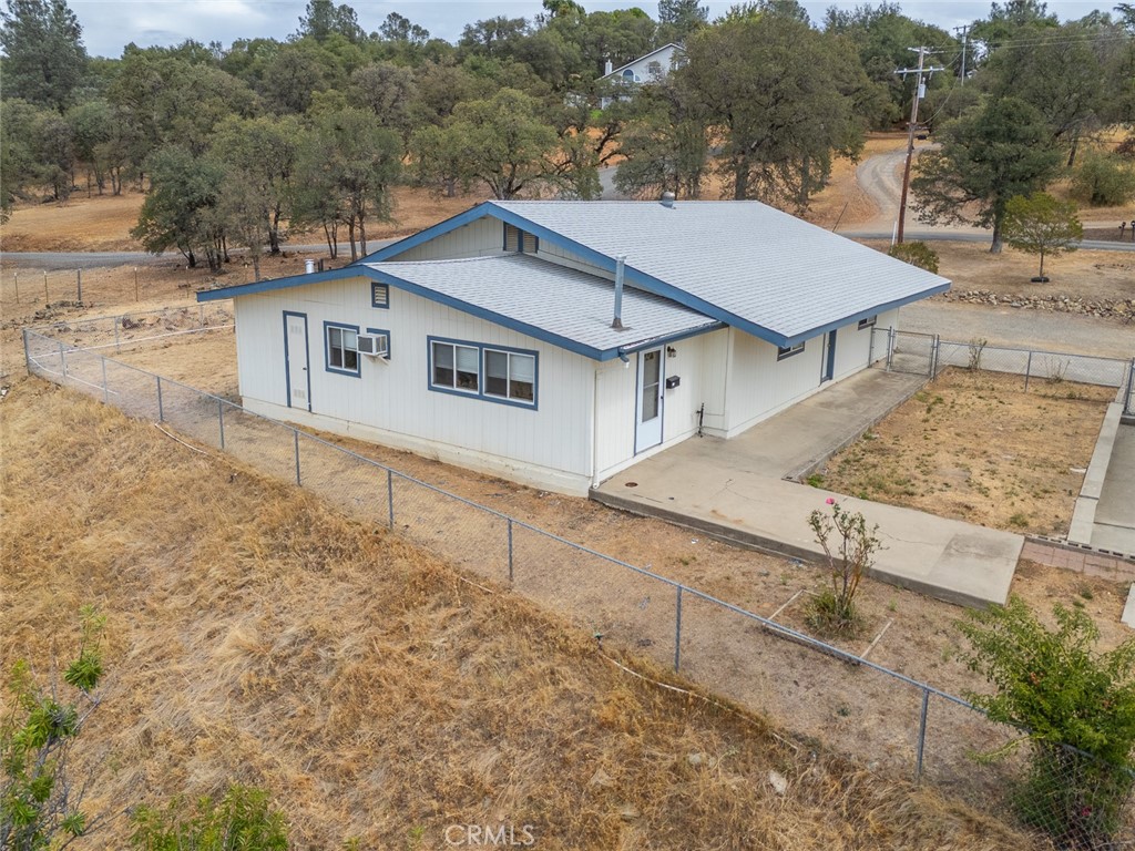 Aerial view of a white single-story home with blue trim on a dry, fenced lot.