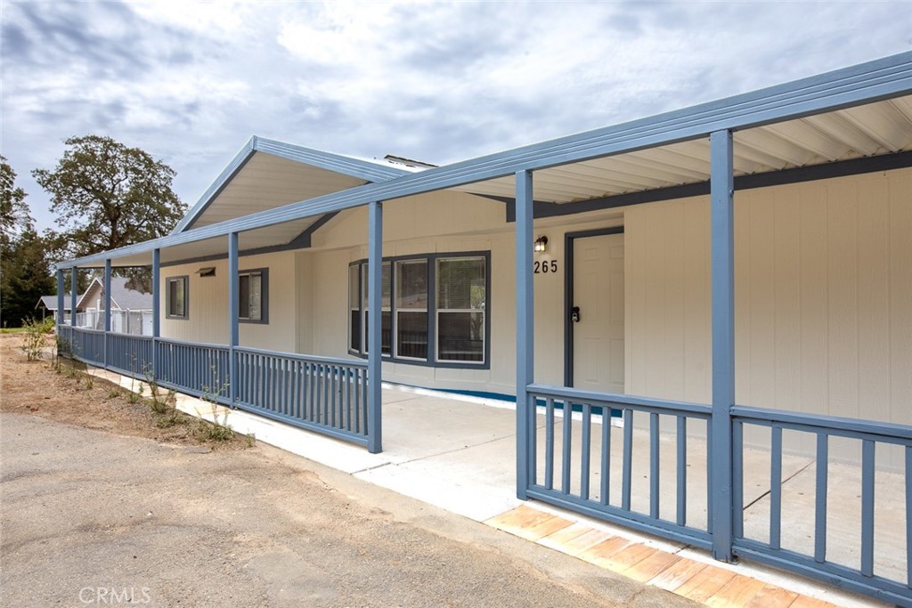 Home exterior with a long covered porch and blue railings, marked with address 265.