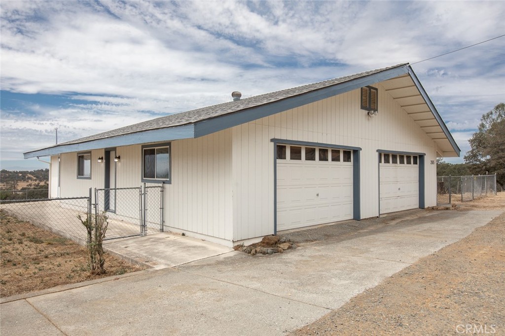 Detached light-colored garage with two doors and a concrete driveway.