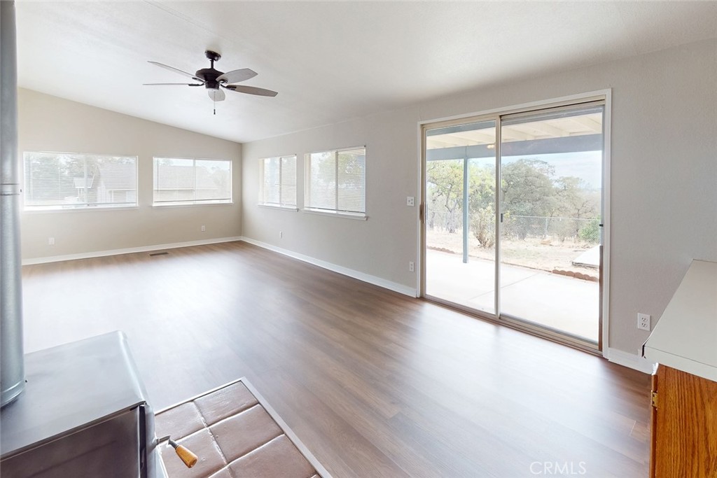 Bright living room with wood-look floors, ceiling fan, and sliding glass door to the patio.