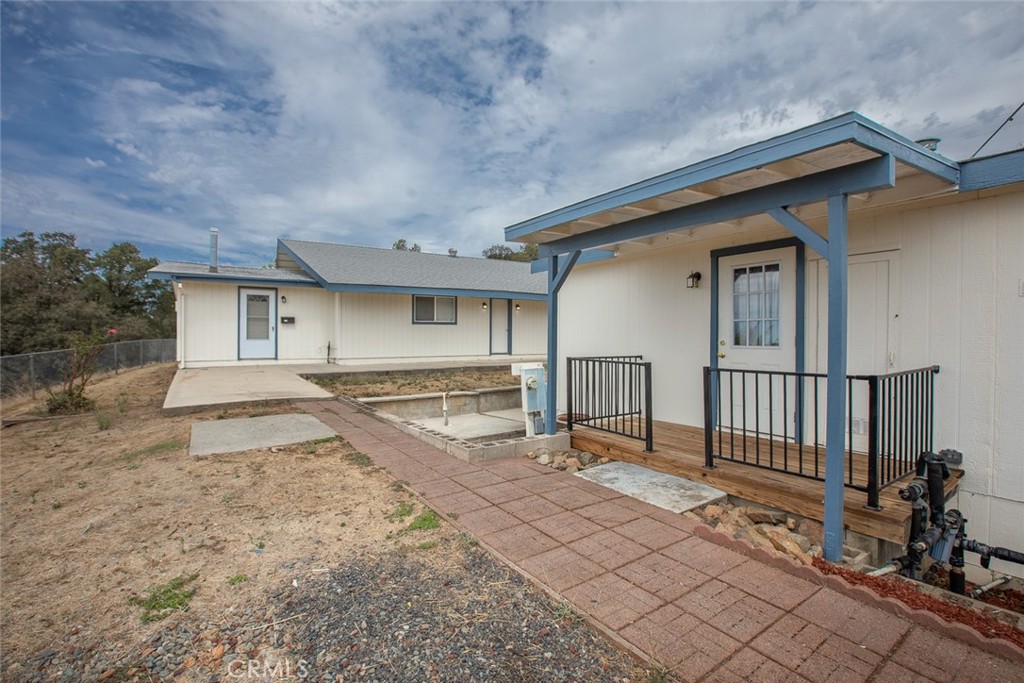 Single-story home with blue-trimmed covered porch and paved walkway across a dry yard.
