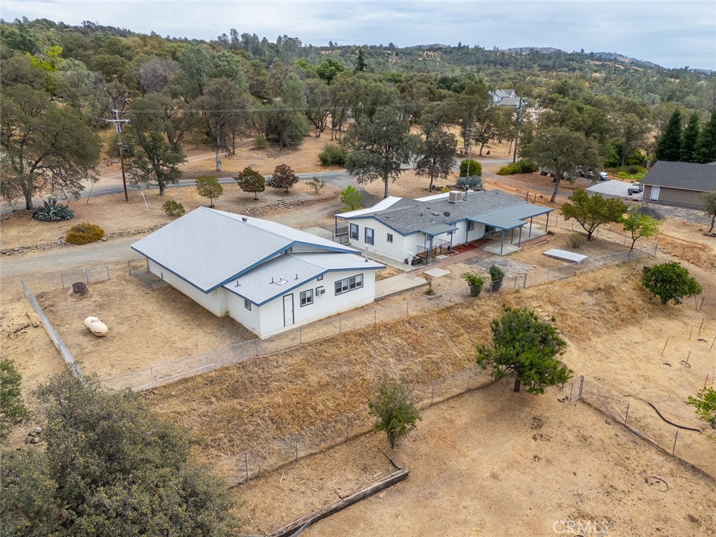 Rural property with two buildings and fenced dry acreage, surrounded by wooded hills.
