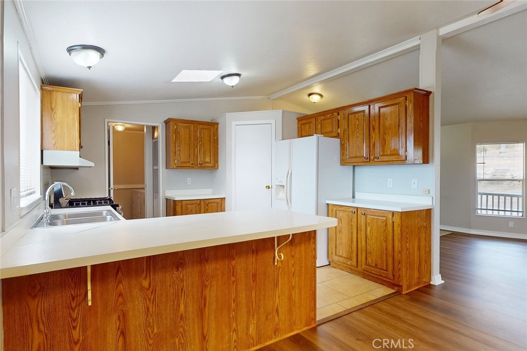 Kitchen with honey-colored wood cabinets, white countertops, and a large peninsula.