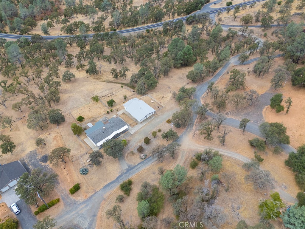 Aerial view of a rural property with several buildings, dry open land, scattered trees, and dirt driveways.