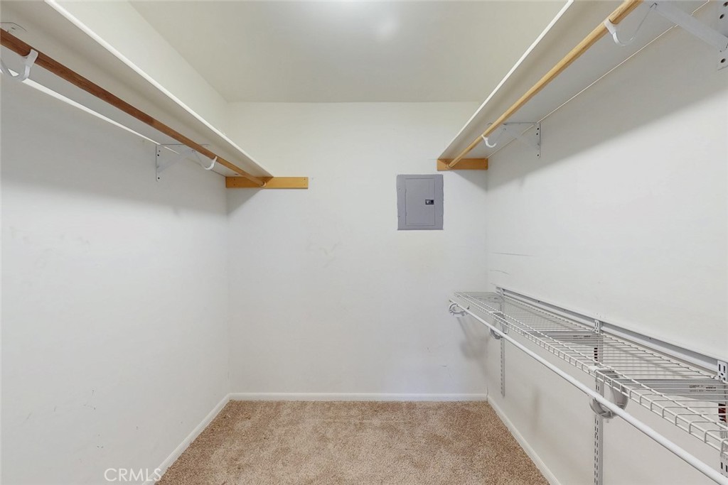 Walk-in closet with wooden hanging rods, wire shelving, and beige carpet.