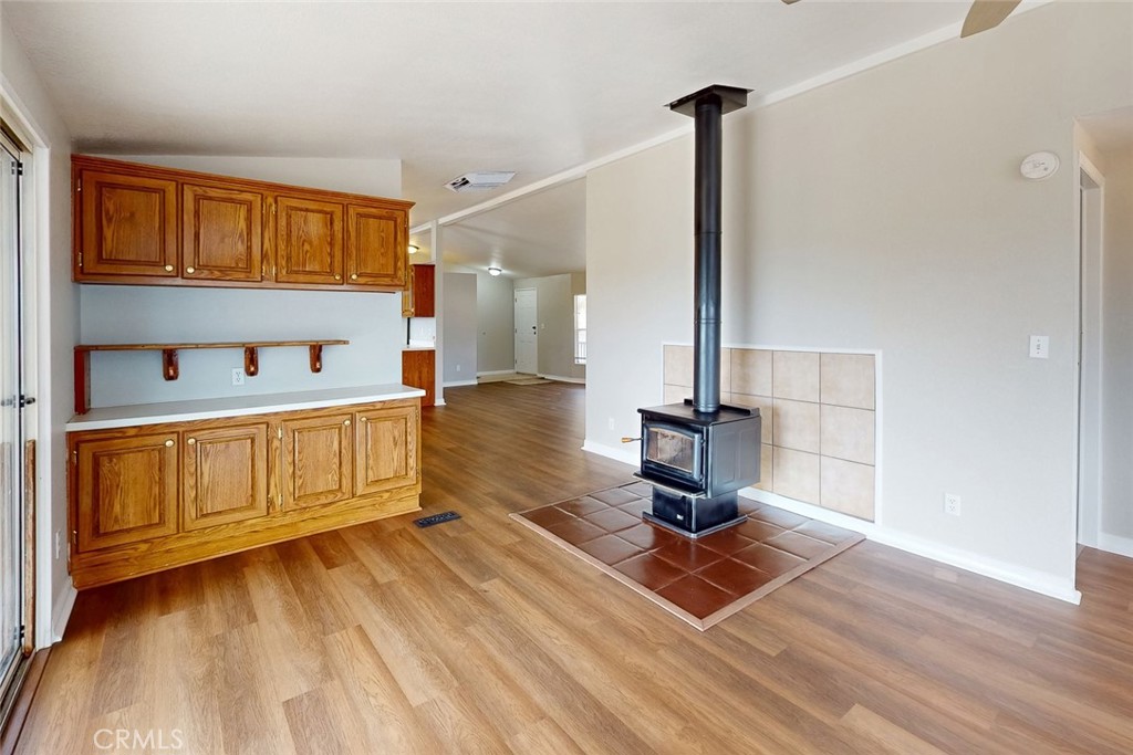 Open living area with built-in oak cabinets and a freestanding wood stove.