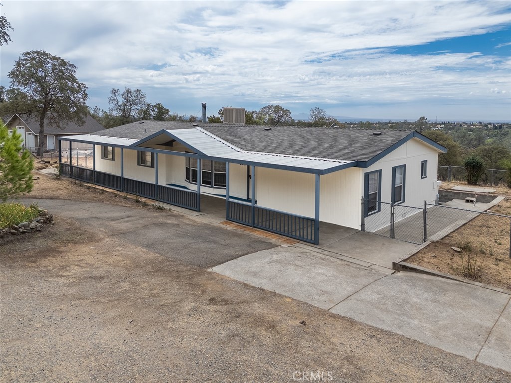 Single-story house with a long covered porch, fenced patio, and broad concrete driveway.