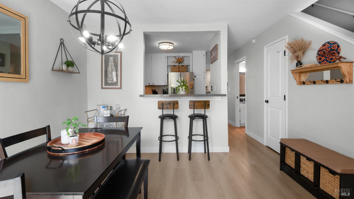 Dining area and open kitchen with a dark table, counter stools, and globe pendant light.
