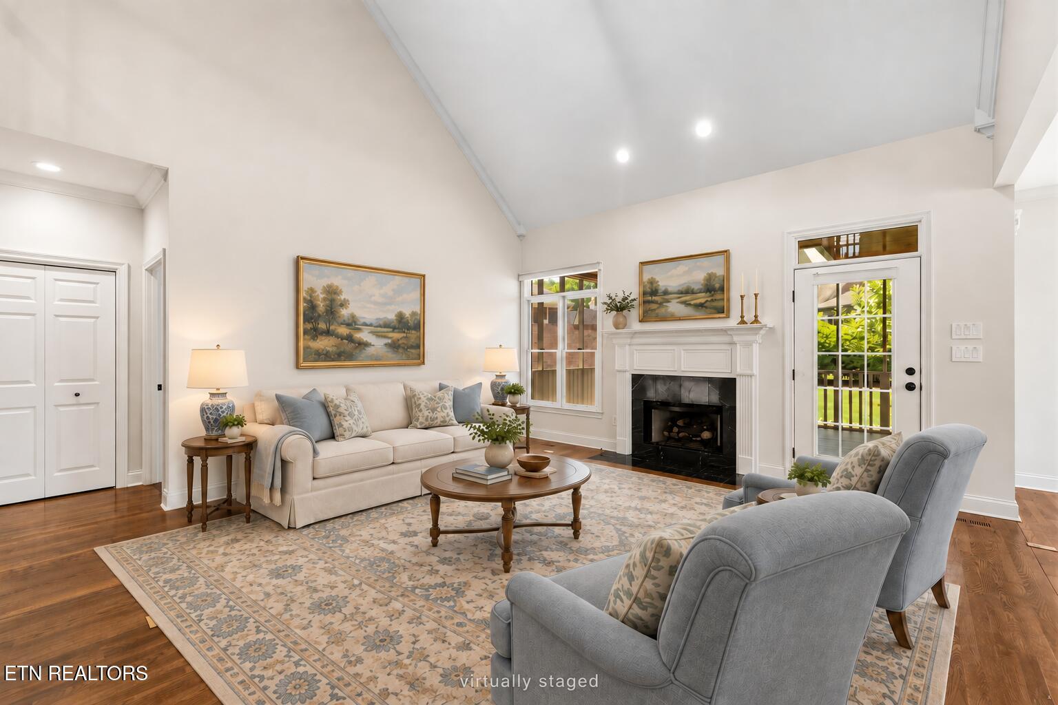 Living room with vaulted ceiling, white fireplace, cream sofa, and blue armchairs.
