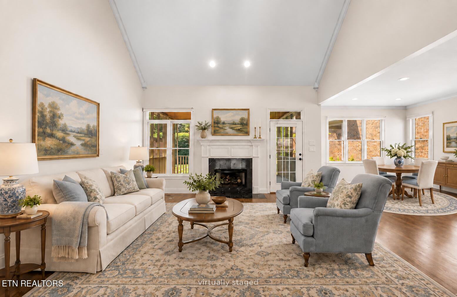 Virtually staged living room with a fireplace, vaulted ceiling, and adjoining dining area.