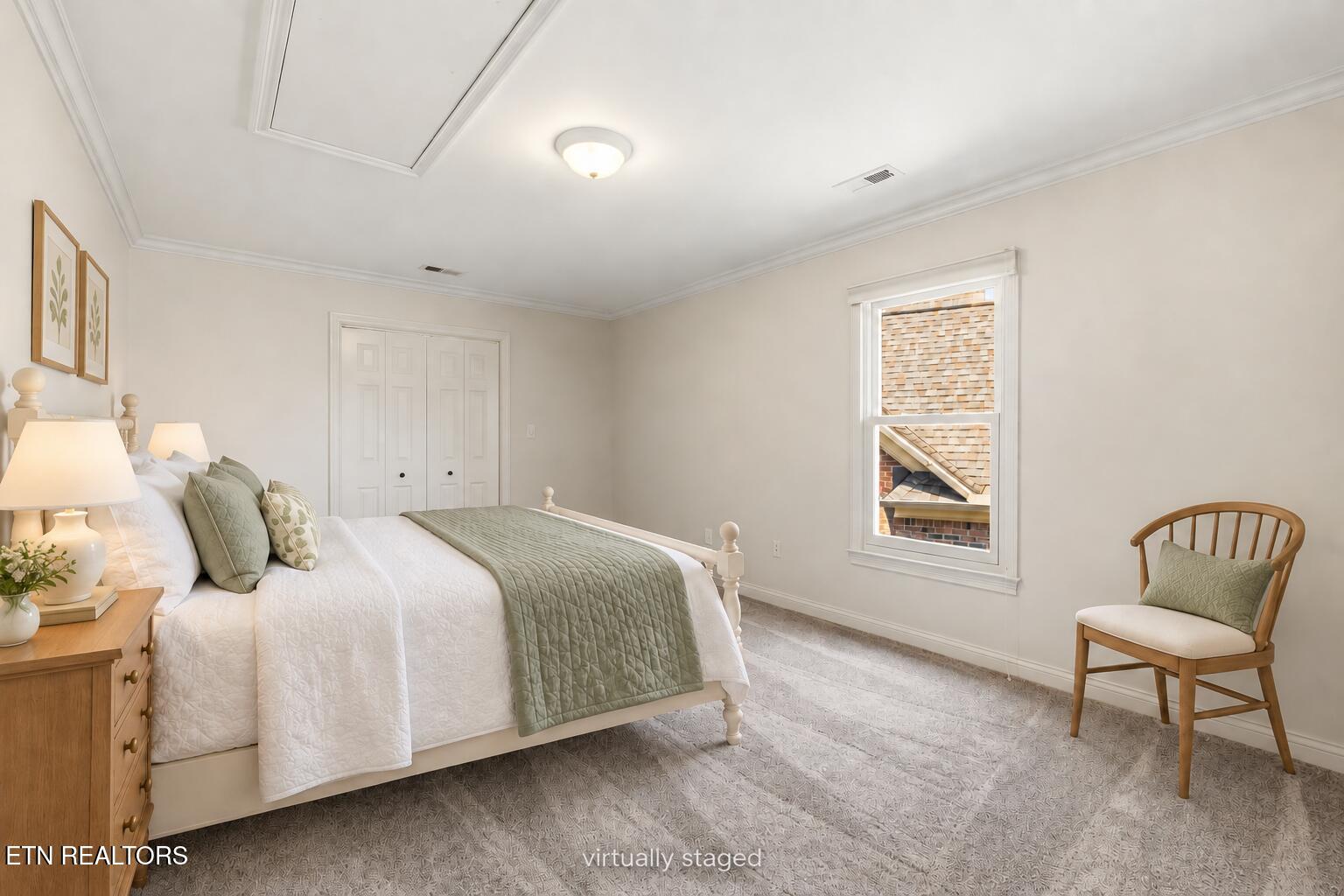 Virtually staged bedroom with a white bed, sage-green quilt, wooden chair, and window.