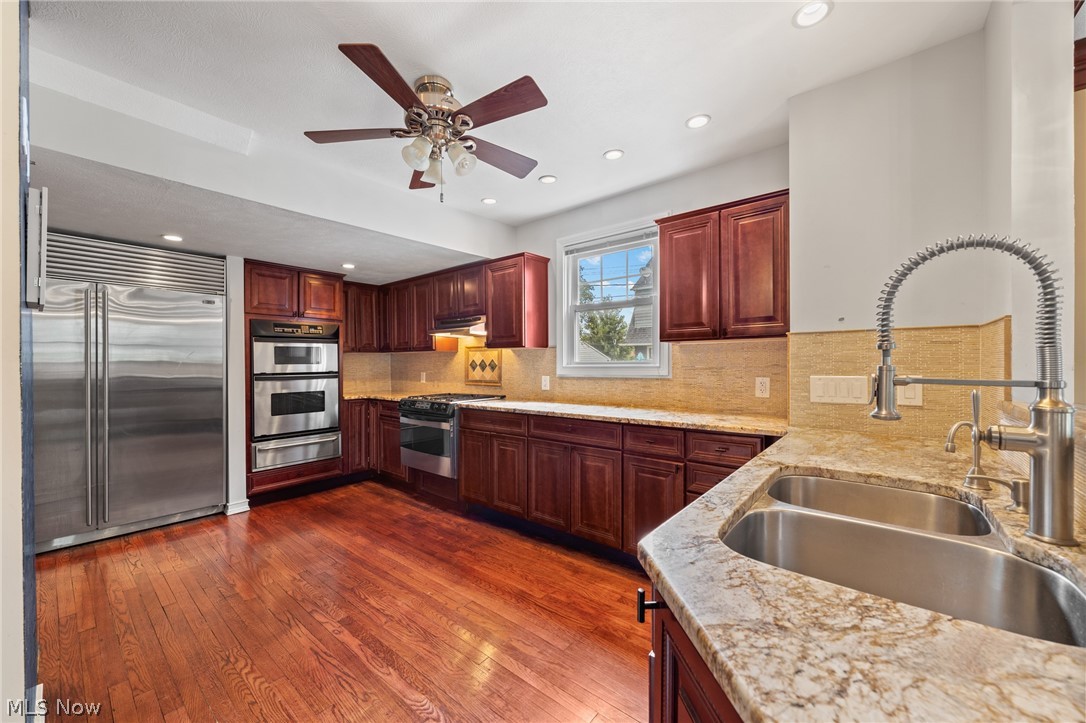 Kitchen with cherry cabinets, stainless steel appliances, granite counters, and hardwood floors.