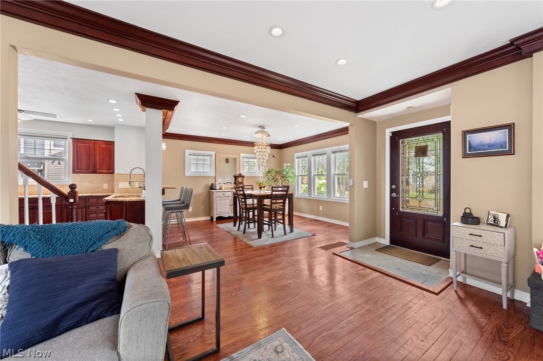 Open living and dining room with hardwood floors, a chandelier, and a decorative glass front door.