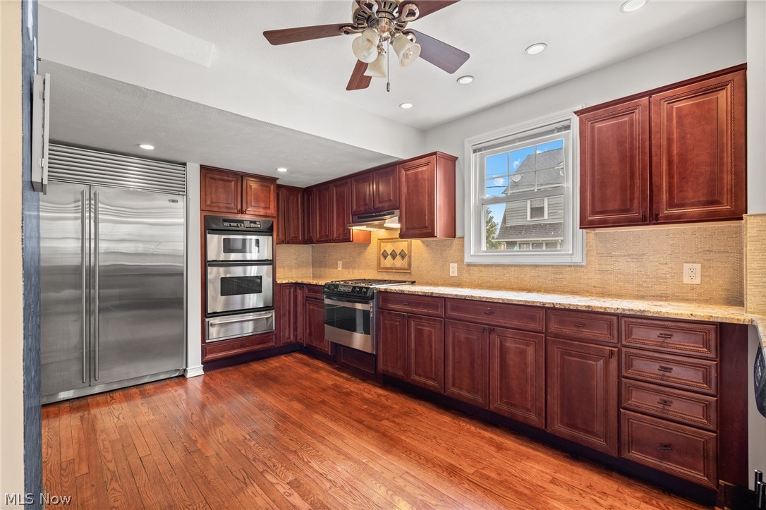 Kitchen with dark wood cabinets, stainless steel appliances, and hardwood floors.