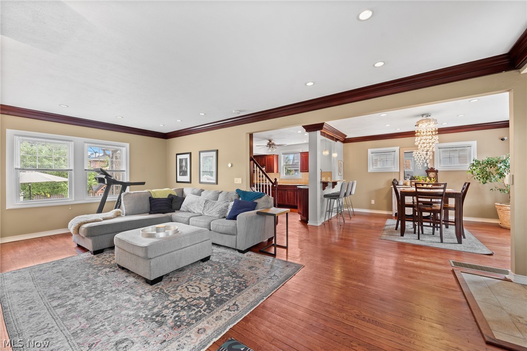 Open-plan living and dining room with a gray sectional, hardwood floors, and a crystal chandelier.