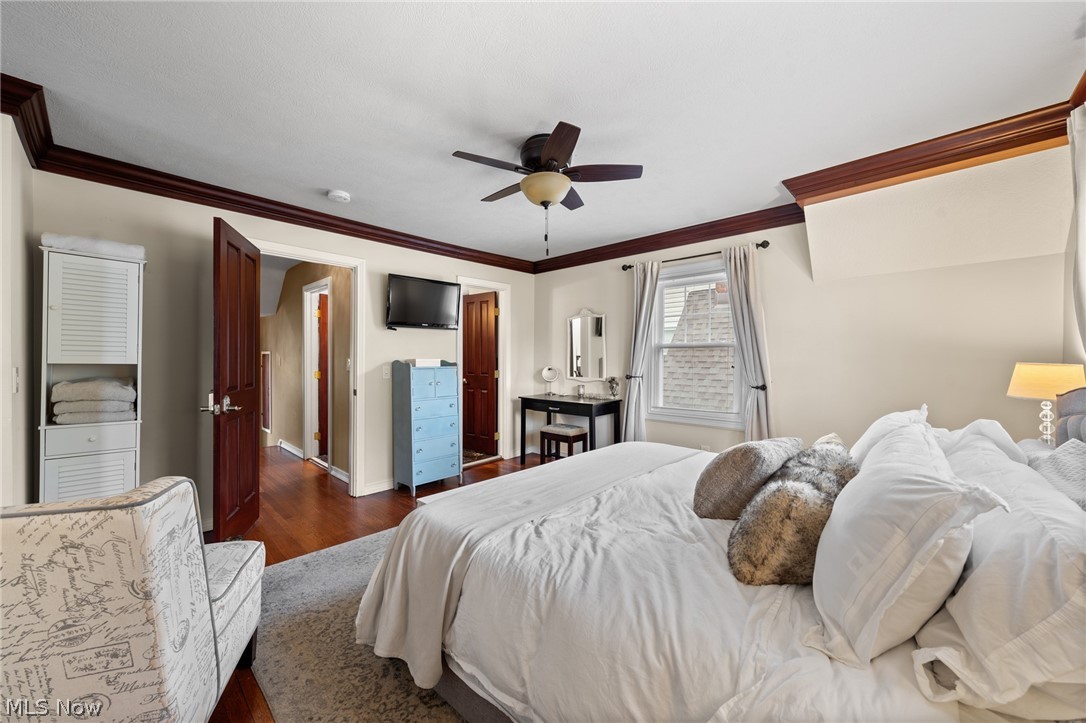 Furnished bedroom with a white bed, dark wood trim, and ceiling fan.