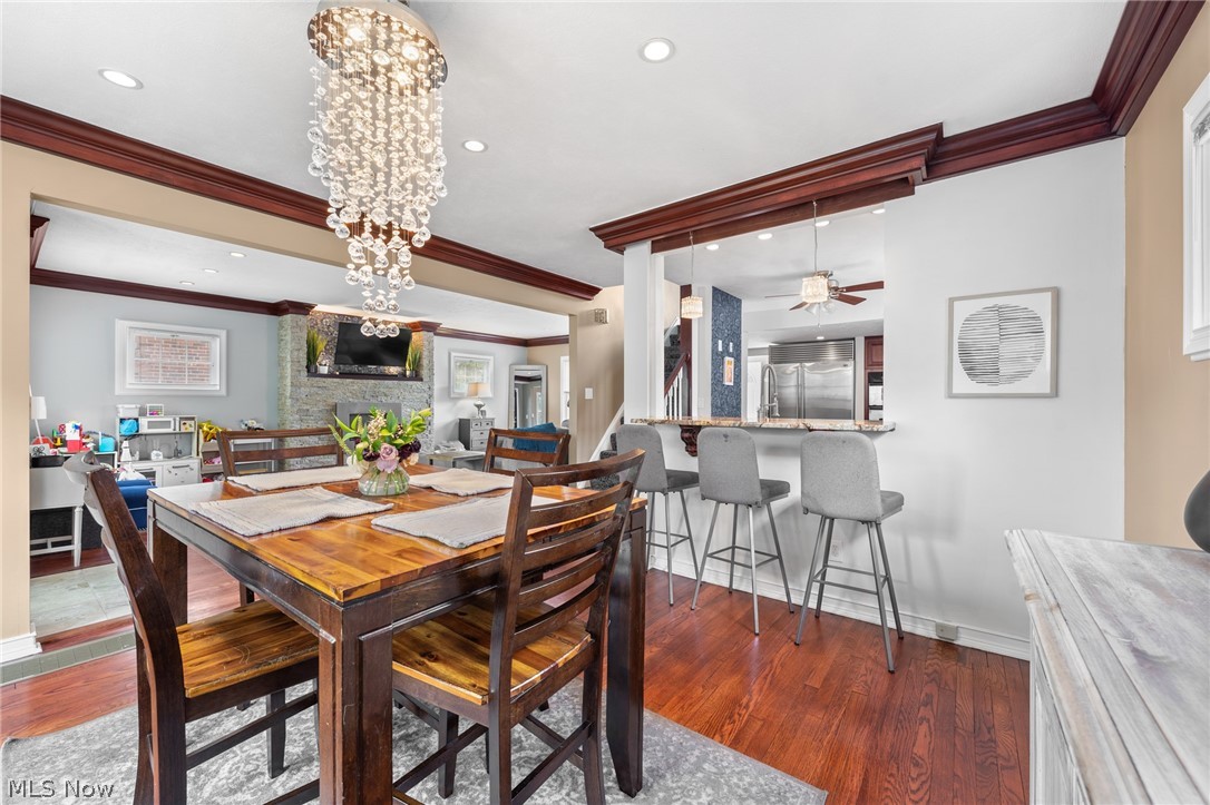 Dining room with a wooden table and crystal chandelier beside an open kitchen breakfast bar.
