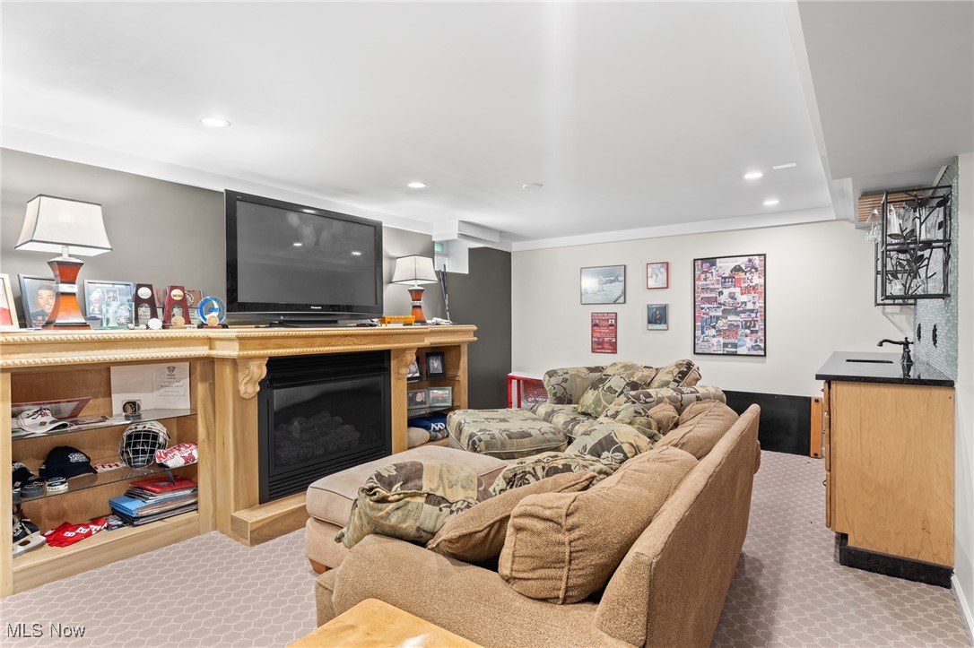 Basement living room with a sectional sofa, built-in fireplace, television, and bar counter.