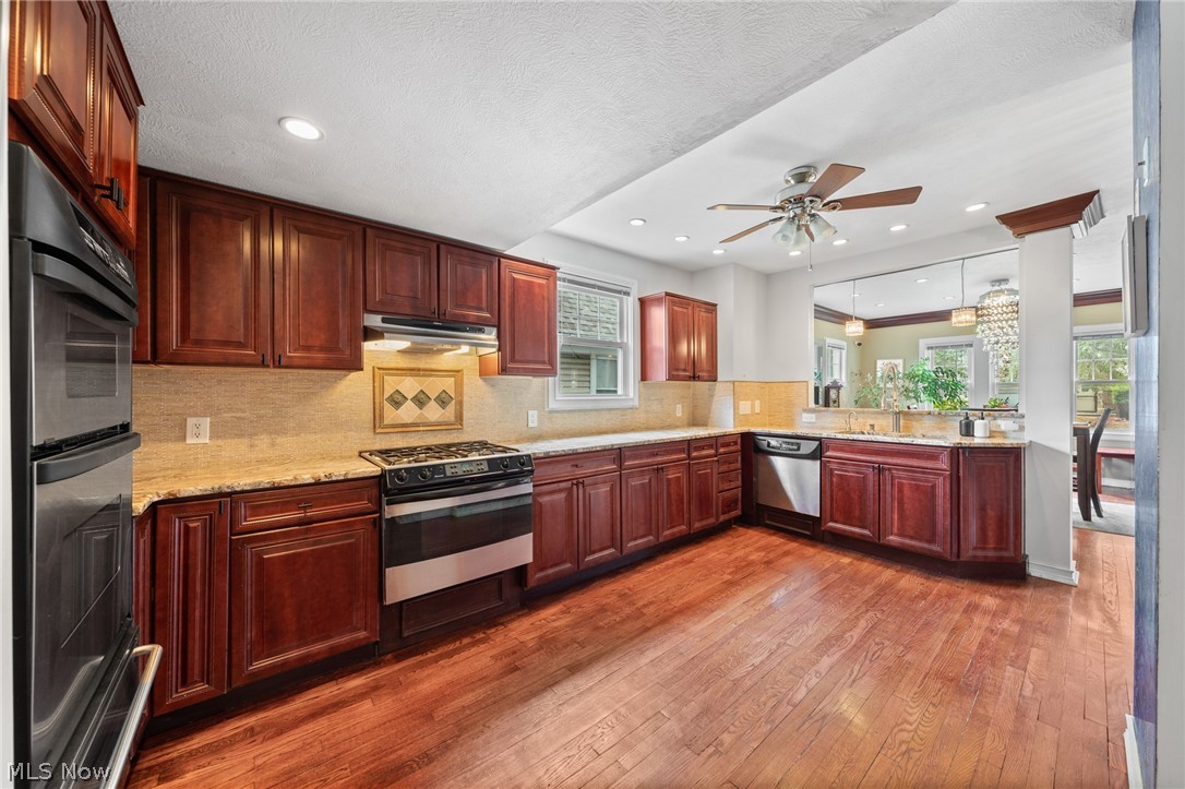 Kitchen with cherry cabinets, stainless steel appliances, hardwood floors, and an adjoining dining area.