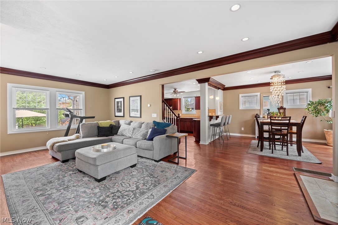 Living room with gray sectional and patterned rug, open to a dining area with a chandelier.
