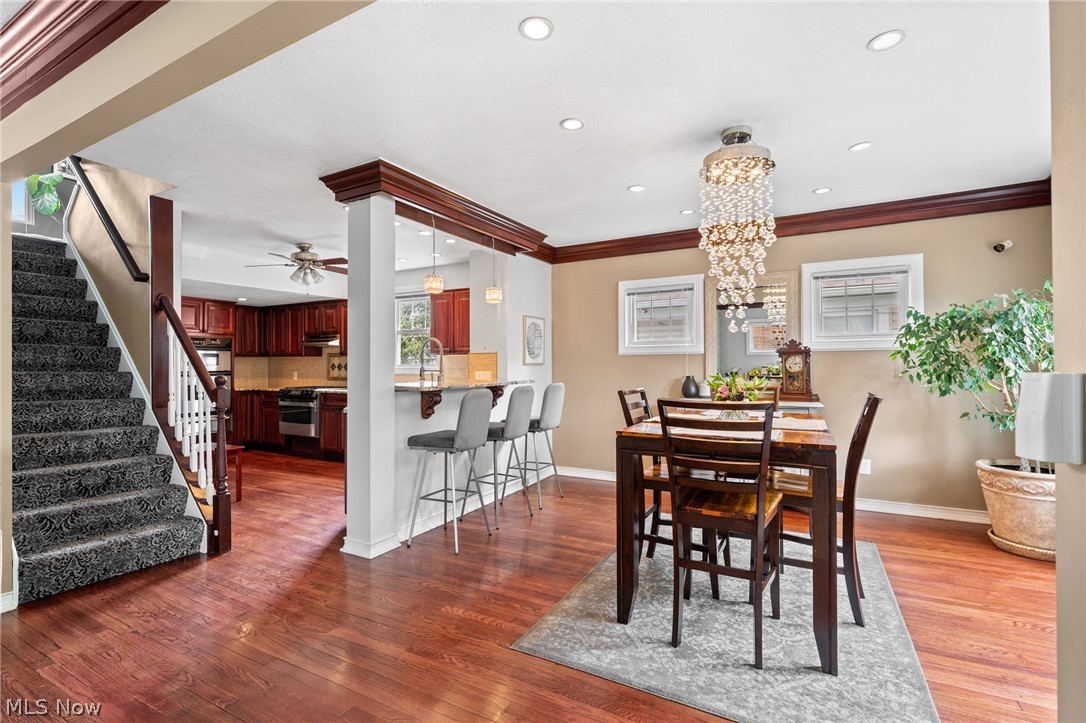 Dining room with a crystal chandelier, hardwood floors, and an open view into the kitchen and staircase.