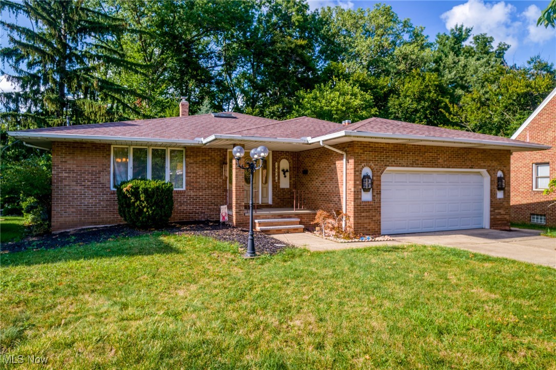 Brick ranch home with an attached two-car garage, covered entry, and broad front lawn.