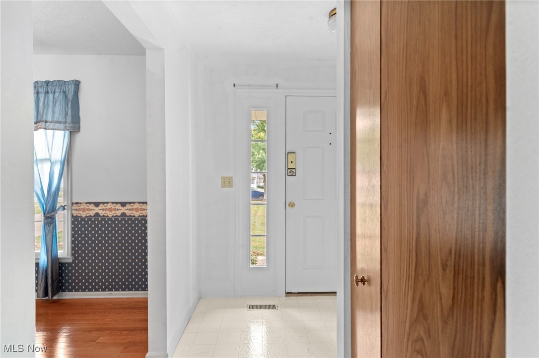 Entry foyer with a white front door, tiled floor, and large wood-grain closet door.
