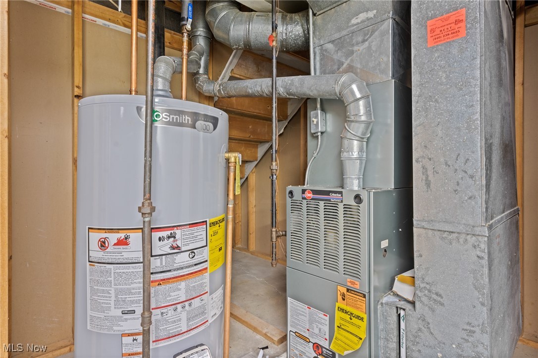 Basement utility area with a water heater beside a gas furnace and exposed ductwork.