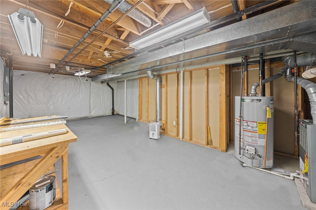 Unfinished basement with exposed joists, prominent HVAC ductwork, and water heater.