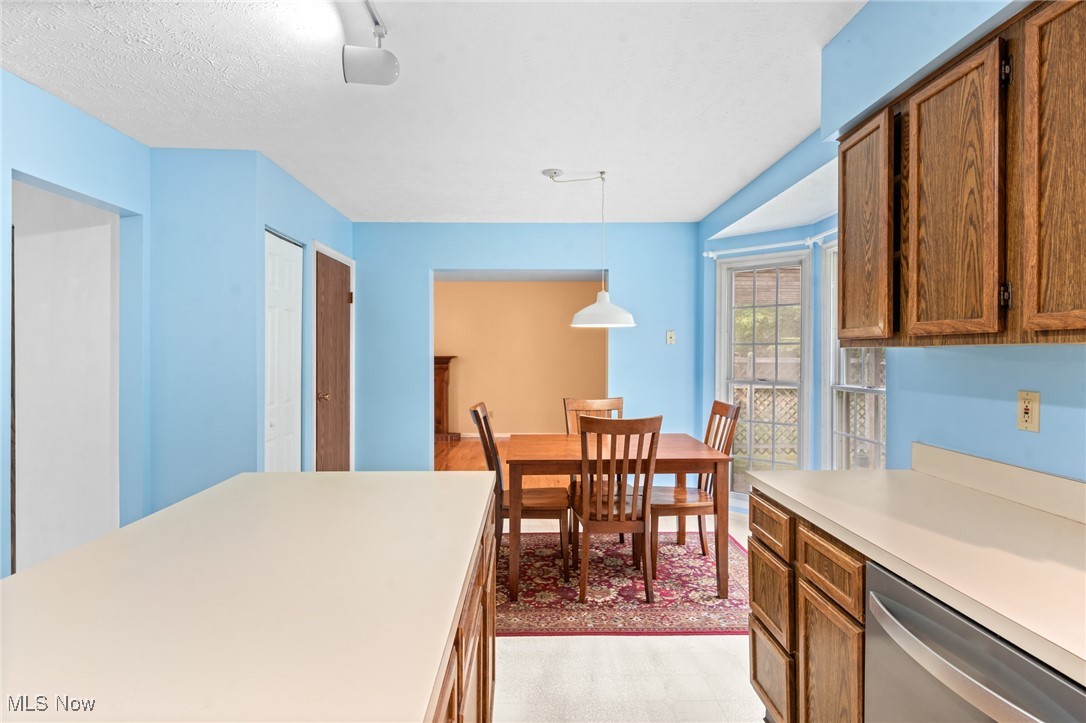 Kitchen with wood cabinets and a dining table beside windows and a glass door.