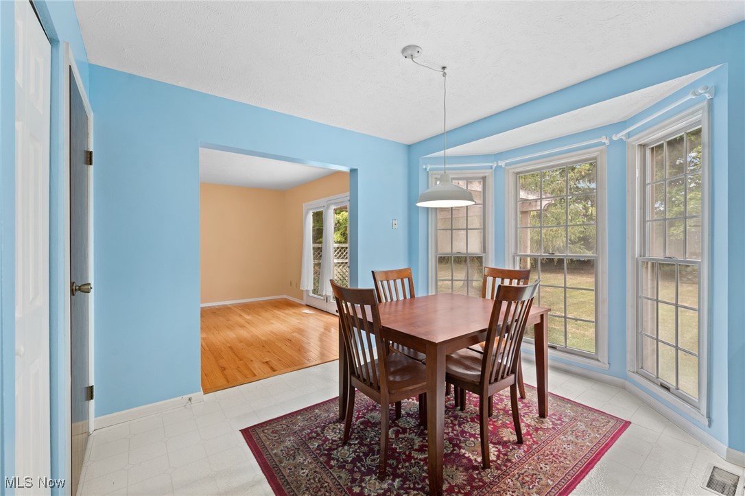 Dining room with a wooden table by three large windows overlooking the yard.