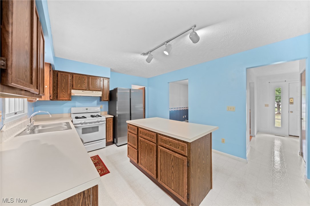 Kitchen with blue walls, dark wood cabinetry, and a central island with a white countertop.