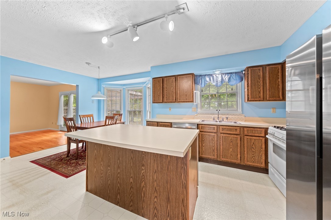 Kitchen with a large island, oak cabinets, stainless steel refrigerator, and adjoining dining area.