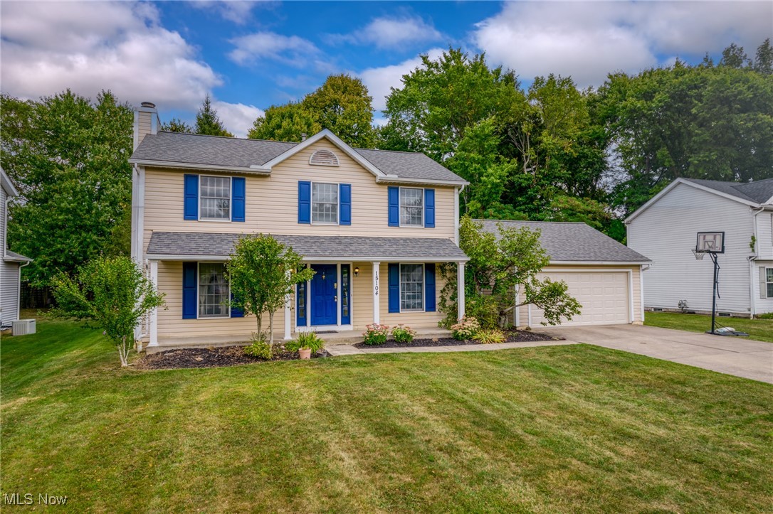 Two-story beige house with blue shutters, a blue front door, and an attached garage.