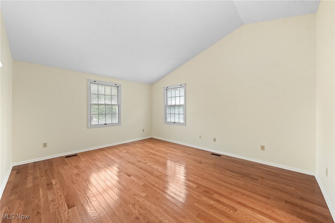 Vacant room with polished hardwood floors and two windows.