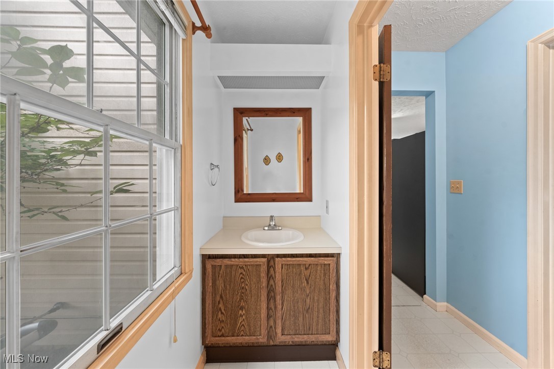Bathroom vanity with a wood-framed mirror beside a large window.