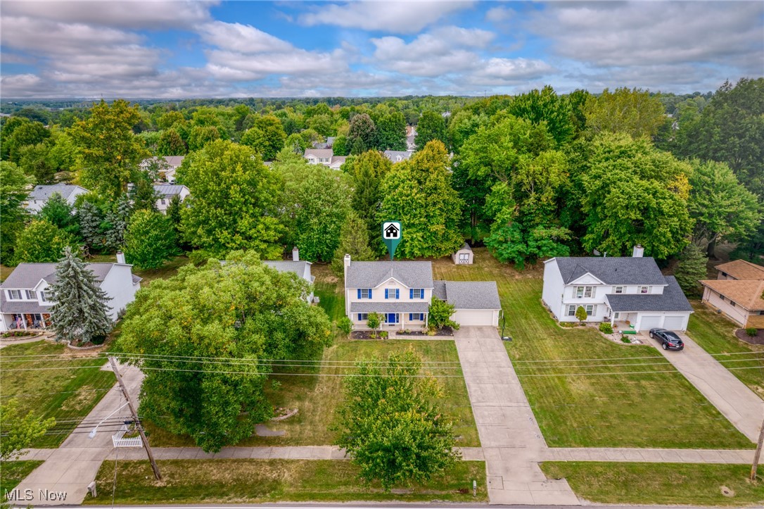 Aerial view of a two-story home with blue shutters and a wooded backyard.
