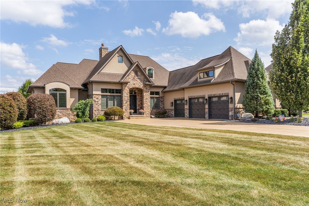 Luxury home with stone-accented facade, three-car garage, and broad landscaped lawn.