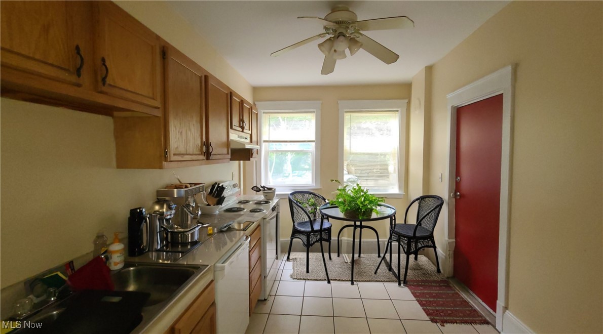 Kitchen with wood cabinets, a double sink, and a small dining nook beside two windows.
