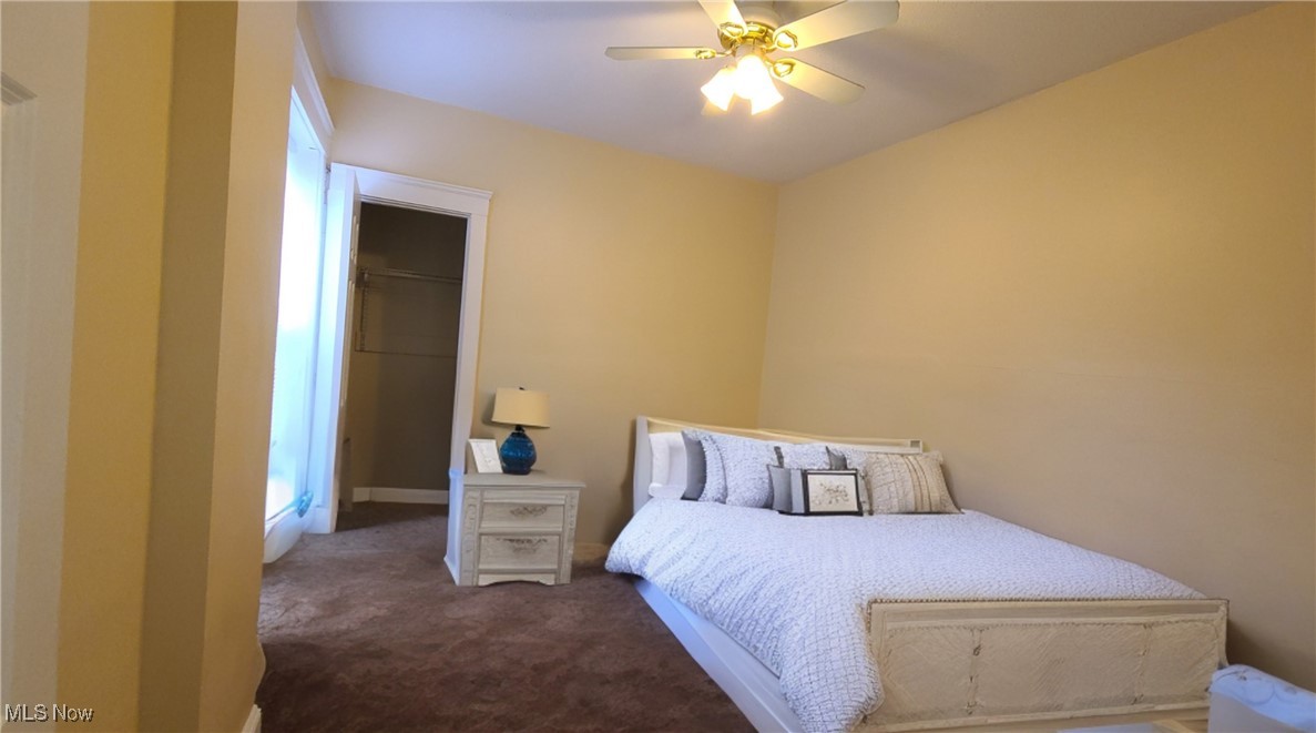 Bedroom with a white bed, ceiling fan, carpet, and open closet.