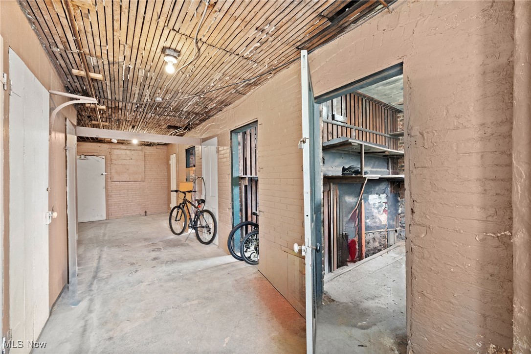 Unfinished utility area with exposed brick walls, a slatted ceiling, and bicycles.