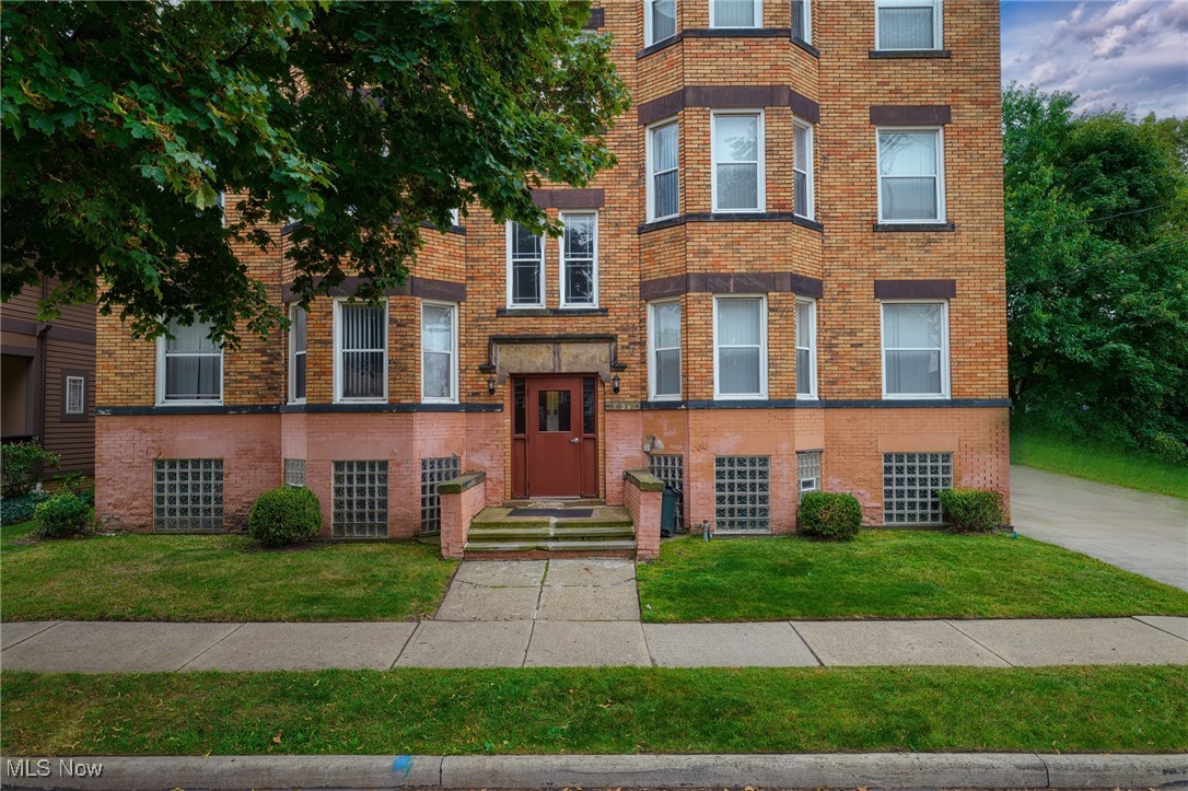 Brick multi-story building with bay windows, a central entrance, and glass-block basement windows.