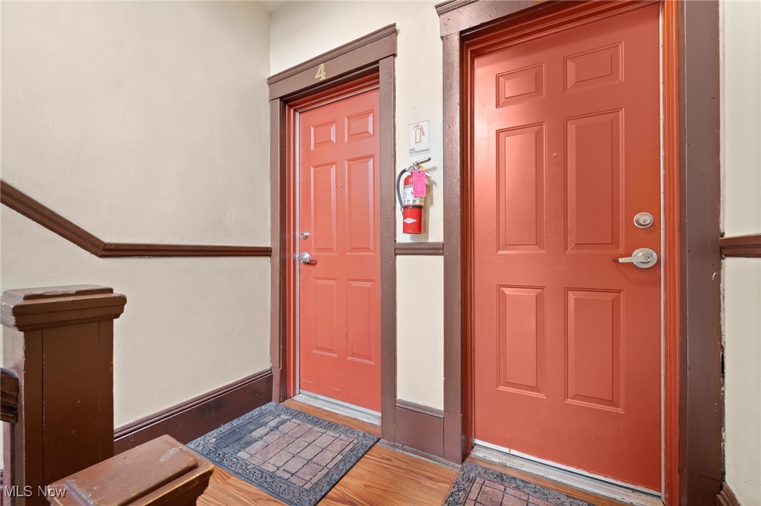 Interior hallway with red paneled doors, dark wood trim, and patterned entry rugs.