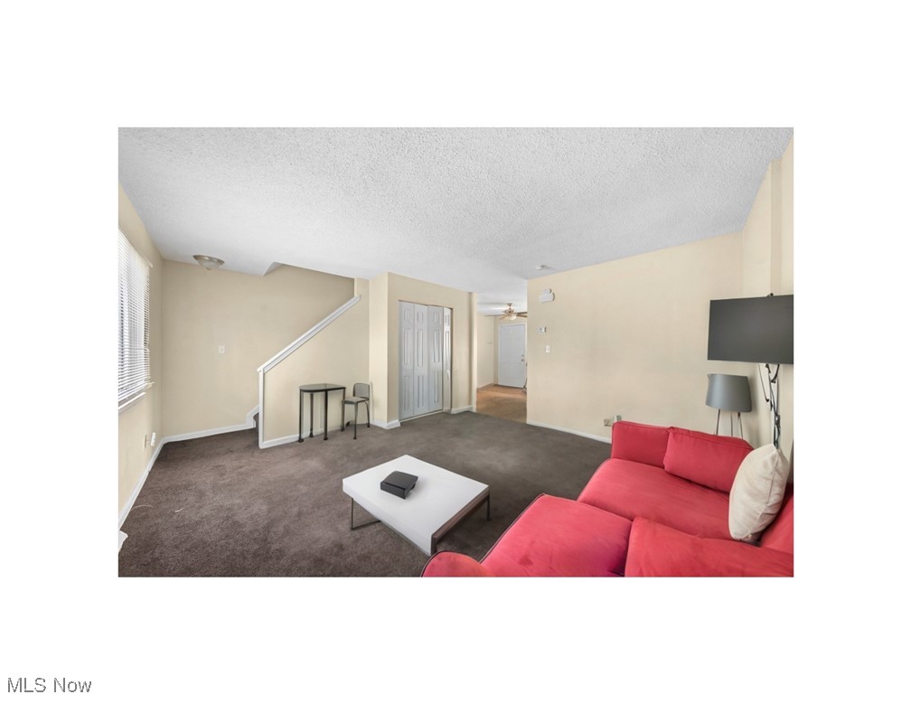 Living room with a red sectional sofa, dark carpet, and white coffee table.