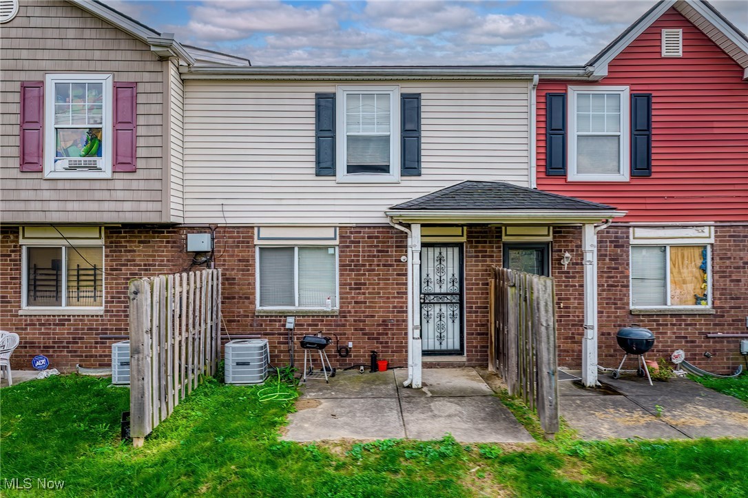 Townhouse rear exterior with a covered entry, fenced patios, and brick lower walls.